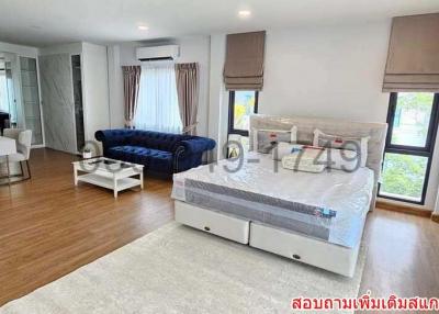 Spacious bedroom with combined living area, hardwood flooring, and natural light