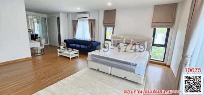 Spacious bedroom with combined living area, hardwood flooring, and natural light