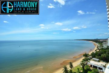 Scenic coastal view from a high-rise balcony showing a clear blue sky and a calm sea adjacent to a sandy beach