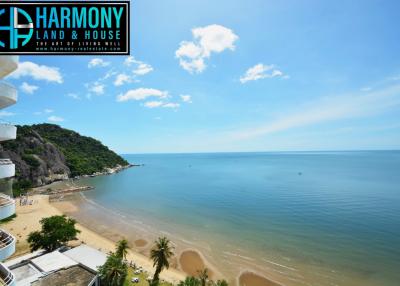 Stunning beachfront view from a high-rise balcony showcasing the clear blue sky, tranquil sea, and sandy shore.