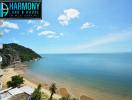 Stunning beachfront view from a high-rise balcony showcasing the clear blue sky, tranquil sea, and sandy shore.