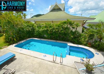 Spacious backyard with a large swimming pool and a well-maintained garden area in front of a house