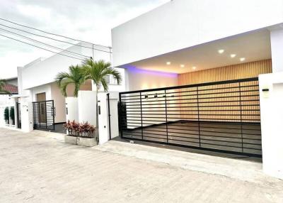 Modern white residential building exterior with illuminated fence
