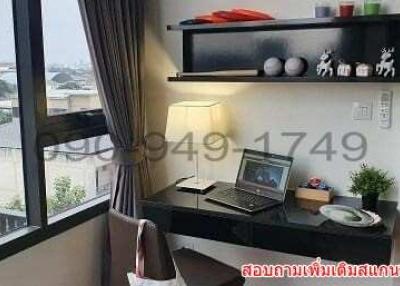 Cozy bedroom workspace with a view, including a desk, laptop, and decorative shelving