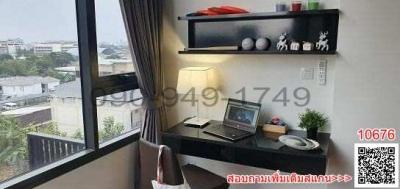 Cozy bedroom workspace with a view, including a desk, laptop, and decorative shelving