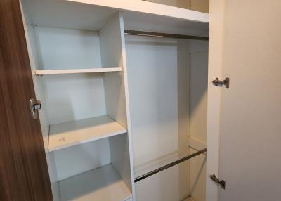 Compact built-in storage closet with open shelving and a mirrored door
