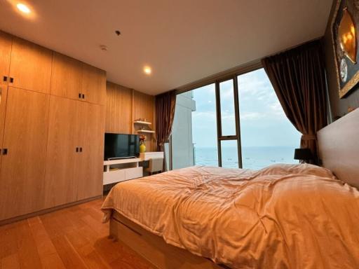 Cozy bedroom with ocean view, wooden flooring, and modern furniture