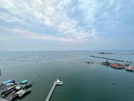 Aerial view of a coastal area showing the sea, a pier, and boats