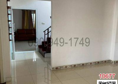 Spacious hallway with tiled flooring leading to a living area with stairs on the left