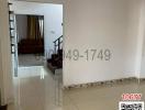 Spacious hallway with tiled flooring leading to a living area with stairs on the left