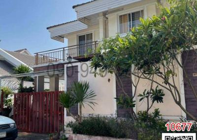 Two-story suburban house with a red gate and greenery