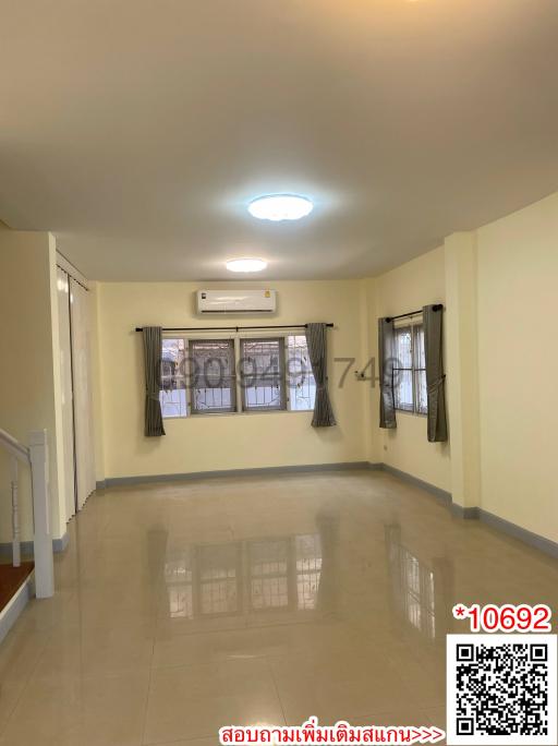 Spacious well-lit living room interior with glossy tiled flooring and air conditioning unit