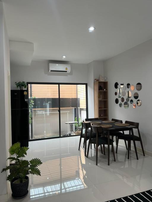 Modern dining area with natural light, adjacent to the balcony