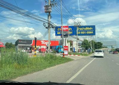 View of a street from the car showing other vehicles, commercial signs, and clear blue sky
