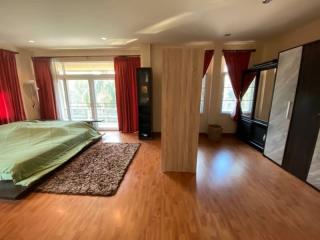 Spacious bedroom with hardwood flooring, natural light, and red curtains