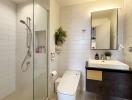 Modern bathroom with glass shower enclosure, white tiles, and plant decor