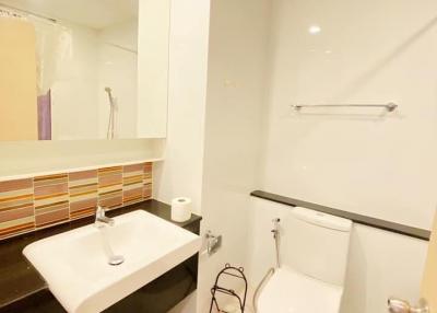 Modern bathroom with white fixtures, including a toilet and sink with a large mirror above