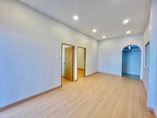 Spacious empty room with hardwood flooring and multiple doors