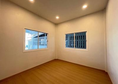Bright empty bedroom with two windows and wooden floor