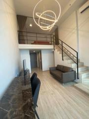 Modern interior design of a high-ceiling living space with mezzanine and unique lighting fixtures