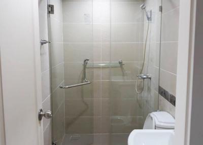Modern white tiled bathroom with a glass shower enclosure and toilet