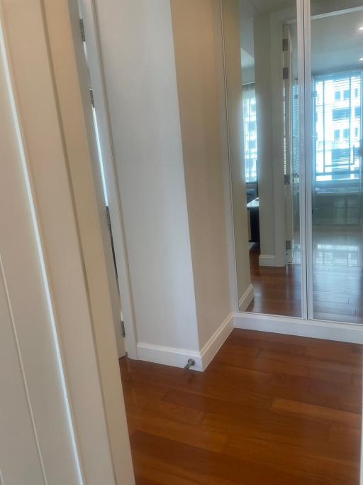 Hallway leading to the living space with hardwood floors and natural light
