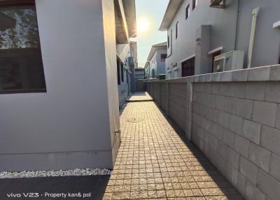 Paved walkway alongside modern residential buildings with a view of the sunset