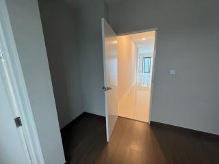 Open door leading to a well-lit bedroom with dark flooring