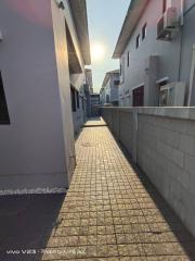 narrow residential pathway between buildings with sunlight