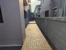 narrow residential pathway between buildings with sunlight