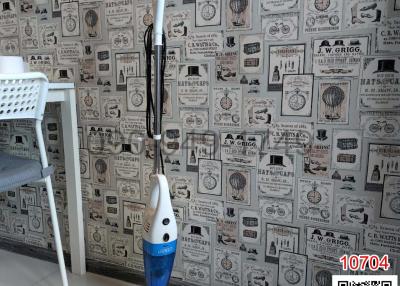 Interior space showing a wall with vintage newspaper-style wallpaper and a vacuum cleaner