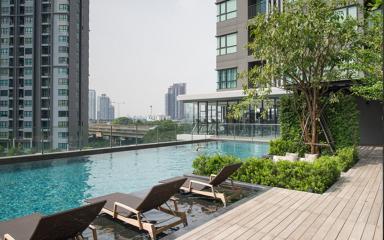 Luxurious outdoor swimming pool with wooden deck and lounge chairs in a modern apartment complex