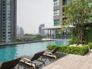 Luxurious outdoor swimming pool with wooden deck and lounge chairs in a modern apartment complex