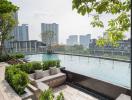 Modern outdoor swimming pool area with city skyline view, surrounded by greenery and a comfortable seating lounge