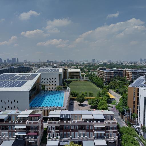 Panoramic view of a residential area with adjacent sports facilities, including a soccer field and a swimming pool