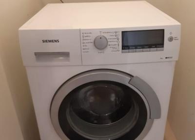 White Siemens front-loading washing machine in a compact laundry area