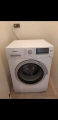 White Siemens front-loading washing machine in a compact laundry area