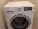 White Siemens front-loading washing machine in a compact laundry area