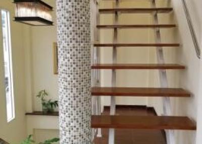 Elegant staircase with wooden steps and decorative tiled column in a modern home