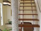 Elegant staircase with wooden steps and decorative tiled column in a modern home