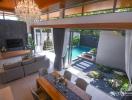 Modern living room with high ceiling and chandelier, connecting to an outdoor area