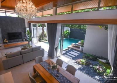 Modern living room with high ceiling and chandelier, connecting to an outdoor area