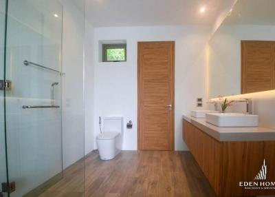 Modern bathroom with glass shower enclosure and wooden cabinets