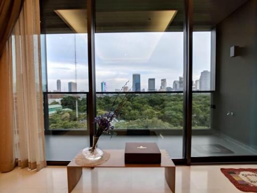 Spacious living room with large windows offering city park views