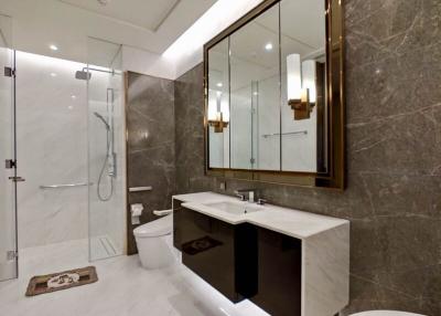 Modern bathroom with marble tiles, large mirror, and glass shower