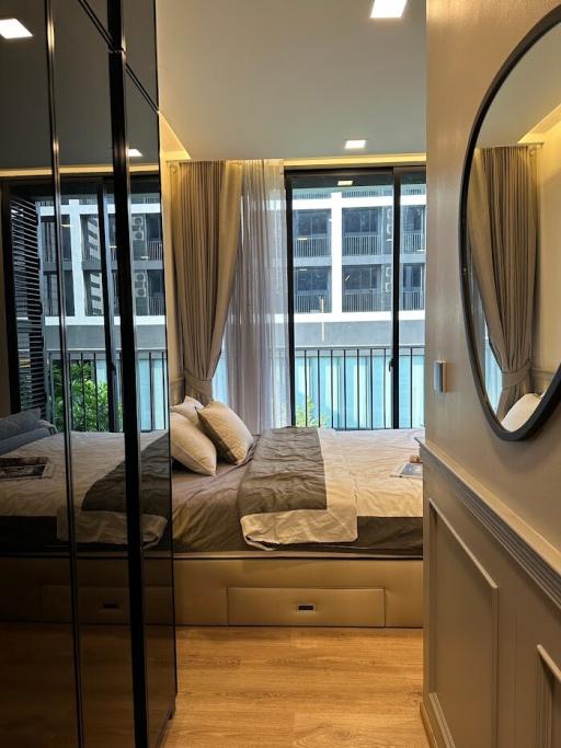 Cozy bedroom interior with a large bed, mirrored wardrobes, and a view of the outside balcony