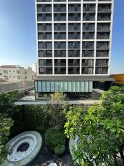 Modern multi-story residential building with lush greenery in the foreground