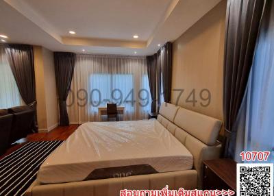 Spacious bedroom with large bed, hardwood floors and natural lighting