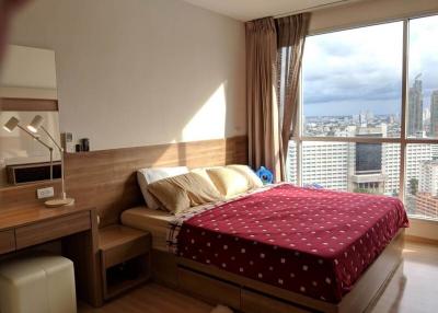 Cozy bedroom with city skyline view, ample natural light and modern furnishings