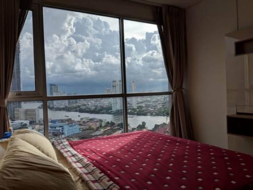 Bedroom with a large window overlooking the city skyline and river